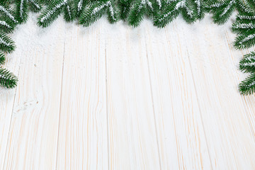 Christmas fir tree with snow on white wooden background. Free space frame