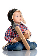 A little boy in a pilot's cap and a wooden plane in his hand