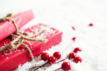 Red gift boxes and christmas fir-tree decoration on a snow surface, soft focus. Christmas background