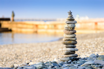 Fototapeta premium Pyramid of sea stones on pebbles of the sea shore. The concept of balance and spirituality.