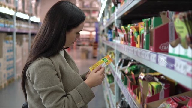 Young woman choosing spices in grocery store, beautiful woman shopping in a supermarket
