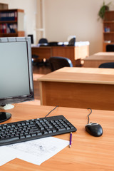 Black off computer monitor with keyboard and mouse on office desk, empty room