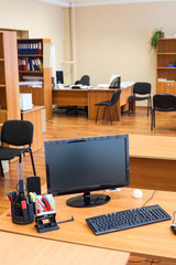 Black lcd computer monitor is off in empty office room after the end of the working day
