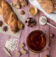 Grain bread with honey and nuts, a mug of tea brown sugar on dark wooden background