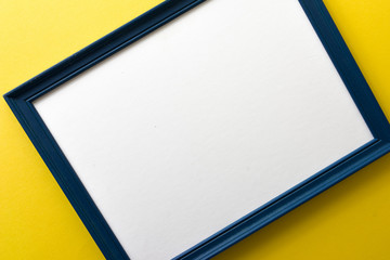 Blue empty picture frame on yellow wall background