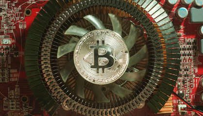 Fototapeta na wymiar silver coin bitcoin are on the heatsink of the video card in the red light