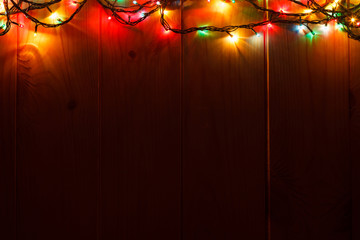 Glowing Christmas garland on the wooden background in the darkness.