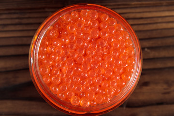 Red caviar in glass jar on wooden table