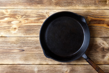 Vintage cast iron pan on wooden rustic background. Top view with copy space.