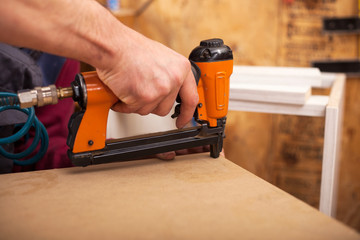carpenter uses a professional stapler or nail gun