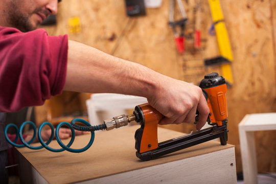 carpenter uses a professional stapler or nail gun