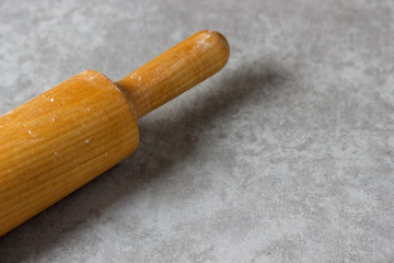 wooden rolling pin dusted with flour on concrete background with blank space for text