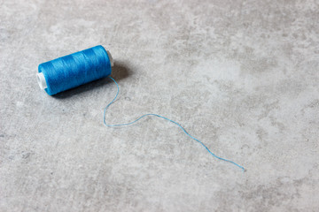 Blue spool of thread on concrete background with blank space for text. Top view