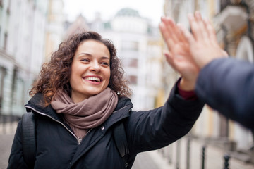Positive girl giving high five on the street. Glad to see you.