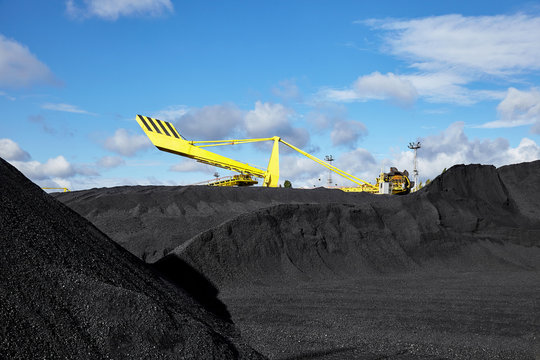 Heap of coal and excavator in coal mine