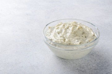 White sauce tartar tartare in a glass bowl on a light stone back