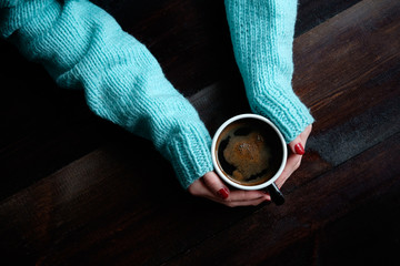 girl in blue sweater holding cup of coffe hands closeup