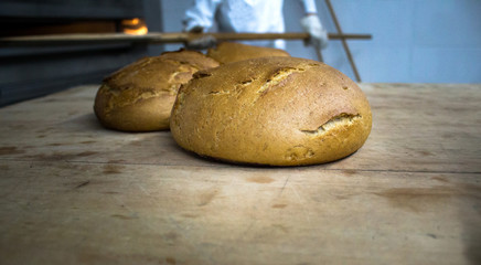 One black bread with flour on a wooden background. Advertising bread. Leaning flour.