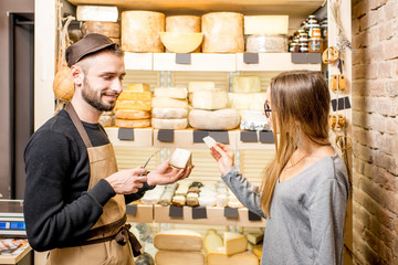Salesman with a woman customer choosing a cheese for buying at the food store