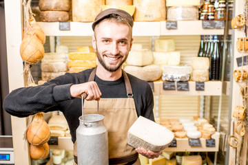 Portrait of a cheese seller with big dairy bucket standing in the cheese shop