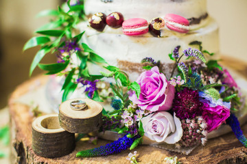 Obraz na płótnie Canvas The beautiful cake with flowers and wedding rings near cake indoors