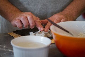 chef hands cooking sushi roll with rice and nori. closeup