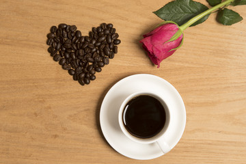 Cup and saucer full of black coffee with coffee beans in the shape of a heart