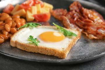 Plate with fried egg, bacon and beans, closeup