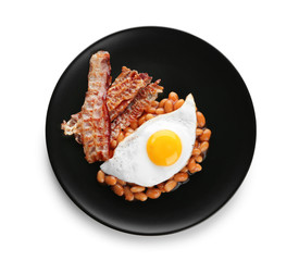 Plate with fried egg, bacon and beans on white background