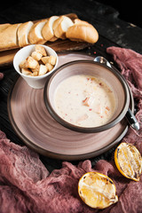 a beautifully served creamy cream soup with salmon in a ceramic plate on a wooden dark table