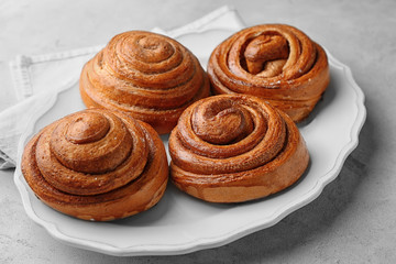 Plate with sweet cinnamon rolls on table