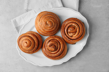 Fototapeta premium Plate with sweet cinnamon rolls on table