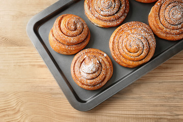 Baking tray with sweet cinnamon rolls on table