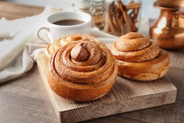 Wooden board with sweet cinnamon rolls on table