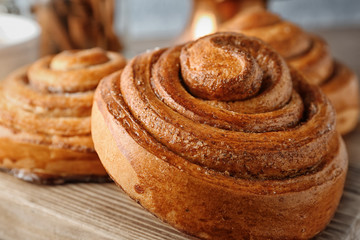 Wooden board with sweet cinnamon roll, closeup