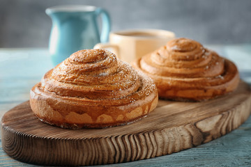 Wooden board with sweet cinnamon rolls on table