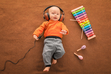 Cute boy with headphones and xylophone on color textile