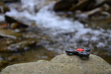 The wooden spinner lies on the rocks against the background of a small waterfall and a river