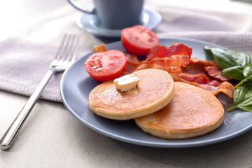 Tasty breakfast with pancakes, bacon and tomato on plate
