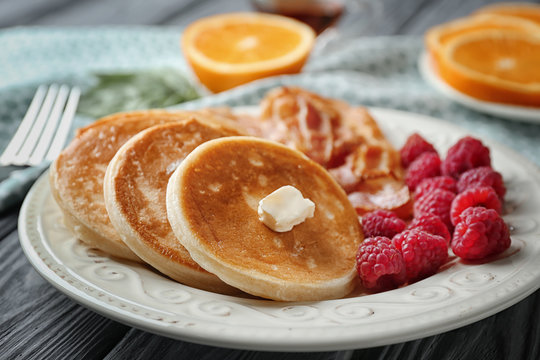 Tasty breakfast with pancakes, bacon and raspberry on plate