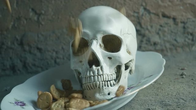 The concept of harmful food. Skull and falling biscuits. Slow motion.