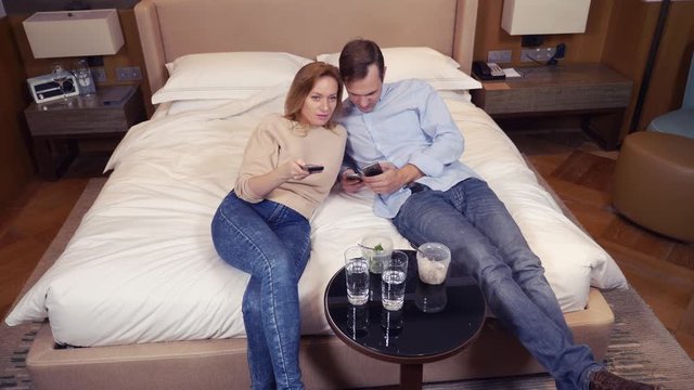 a couple of man and woman, vegetarians, sitting in the evening on the bed, watching TV and eating broccoli. 4k