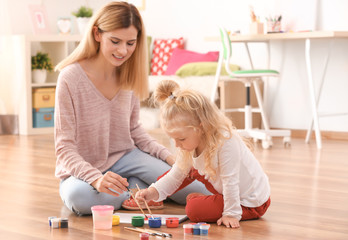 Mother with cute girl painting picture on sheet of paper, indoors