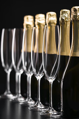 Bottles of champagne and empty glasses on a black background. Selective focus