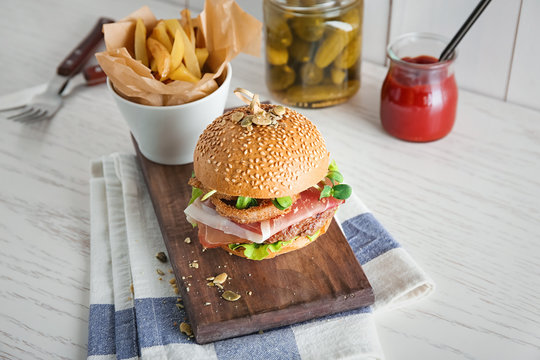 Tasty burger with prosciutto on wooden board