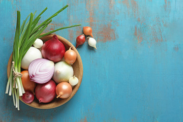 Bowl with different onions on color wooden table