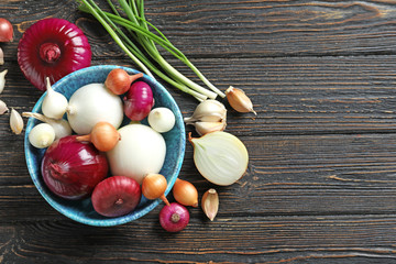 Composition with different onions on wooden table