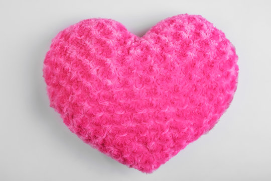 Soft pillow in shape of heart on light background