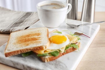 Board with delicious toasts and fried egg on table