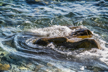 Fototapeta premium Scenic water splash and a rock in ocean